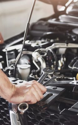 Close up hands of unrecognizable mechanic doing car service and maintenance.